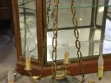a chandelier with candles and a glass case in the background