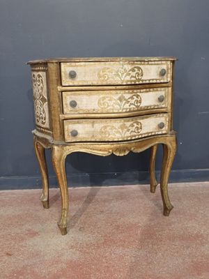 a small chest of drawers on a stand against a wall