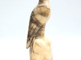 statue of a bird perched on a rock on a white background