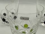 four glasses with black and green dots on them on a table