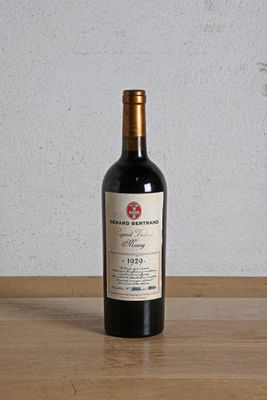 a bottle of red wine sitting on a wooden table