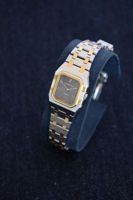 a silver and gold watch on a black surface