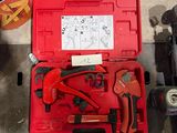 une boîte à outils rouge contenant des outils, posée par terre