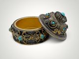 two silver and turquoise bracelets with gold accents on a white background