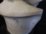 a white marble bust of a woman with a flower on her head