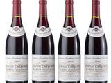 four bottles of wine are lined up on a white surface