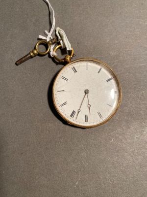 a small pocket watch with a key hanging from it ' s chain