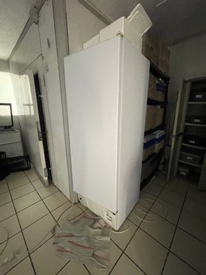 un réfrigérateur blanc au milieu d'une pièce encombrée