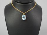 un collier en or orné d'une topaze bleue, posé sur un mannequin