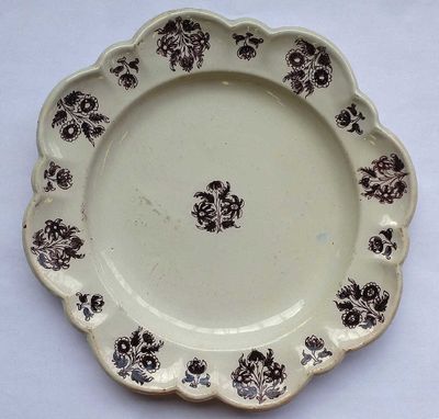 une assiette marron et blanche ornée de fleurs noires, posée sur une table blanche
