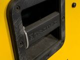 a close up of a yellow jeep door with a black handle