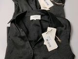 two black shirts with tags on them sitting on a table