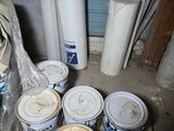 many buckets of paint sitting on a pallet in a room