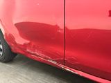 a close up of a red car that has a denting on it