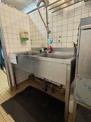 un lavabo en acier inoxydable dans une salle de bains aux murs carrelés
