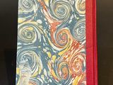 a small notebook with a red cover and a swirl pattern on it