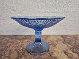 un bol en verre bleu posé sur une table, avec un mur blanc en arrière-plan