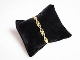 un gros plan sur un oreiller noir sur lequel repose un bracelet doré