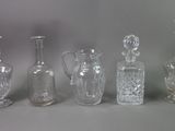 five different glass vases and a bottle on a table