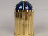 gold and blue glass container on a white surface