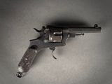 un pistolet posé sur une surface grise, sur fond noir