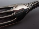 a silver fork with a flower on it on a table