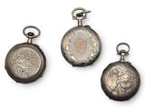 three antique silver pocket watches on display against a white background