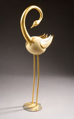 une statue en or représentant un oiseau au long cou et aux longues pattes