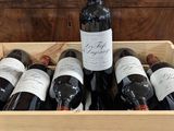 des bouteilles de vin dans une caisse en bois posée sur une nappe rouge