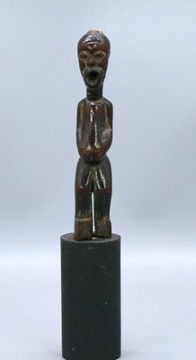 une image représentant une petite statue en bois d'un homme sur un socle
