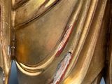 a gold statue of a person holding a flower