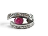 silver ring with a ruby stone and diamonds on a white background