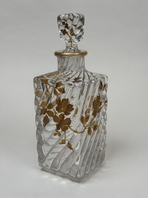 une image représentant une bouteille en verre ornée de fleurs dorées