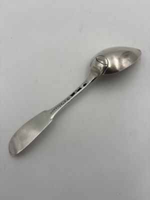 une vieille cuillère au manche en métal posée sur une surface blanche