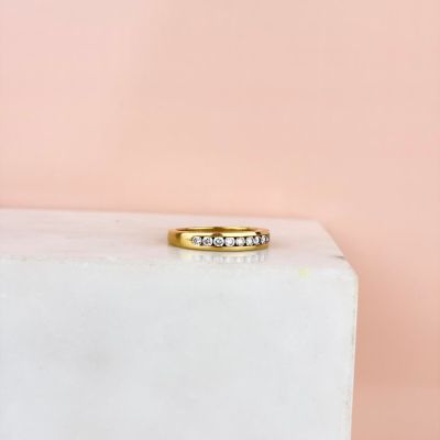 une bague en or sertie de trois diamants, posée sur un bloc de marbre blanc