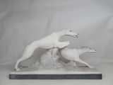 sculpture of two white greyhounds running on a rock with a white background