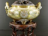 un grand bol en laiton posé sur un socle en bois orné d'un dragon