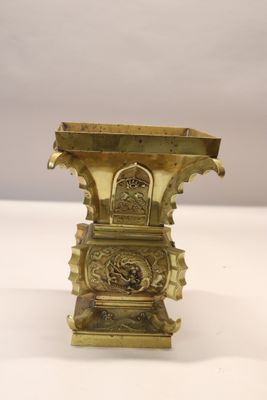a gold vase that is sitting on a white table