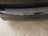 the rear end of a black car with a chrome bumper