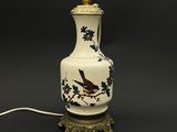 un vase blanc orné d'un oiseau, posé sur une table