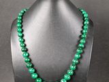 a green beaded necklace on a mannequin display