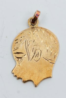 un gros plan d'un pendentif plaqué or représentant une tête d'homme