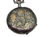 a silver pocket watch with a floral design on it