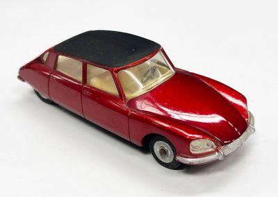 une petite voiture rouge avec un toit noir posée sur une surface blanche