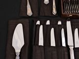 a lot of silverware on a table with a black cloth