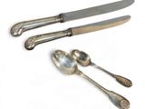two silver spoons and a knife on a white surface