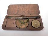 une petite boîte en bois contenant une boussole et un stylo