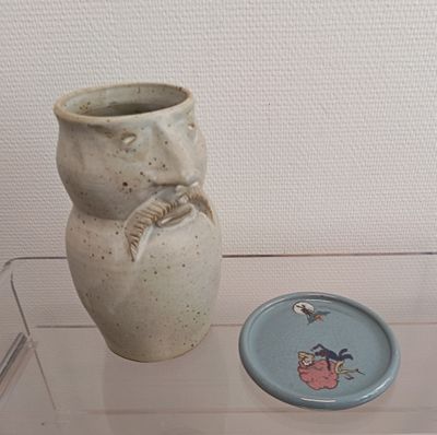 a vase and a plate on display in a glass case
