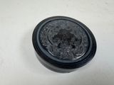 une image représentant un récipient noir posé sur une surface blanche