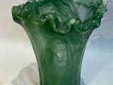 un vase vert posé sur une surface blanche
